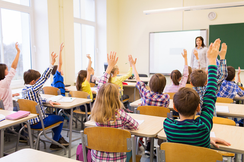 Unterrichtsstunde mit Schüler:innen die aufzeigen.